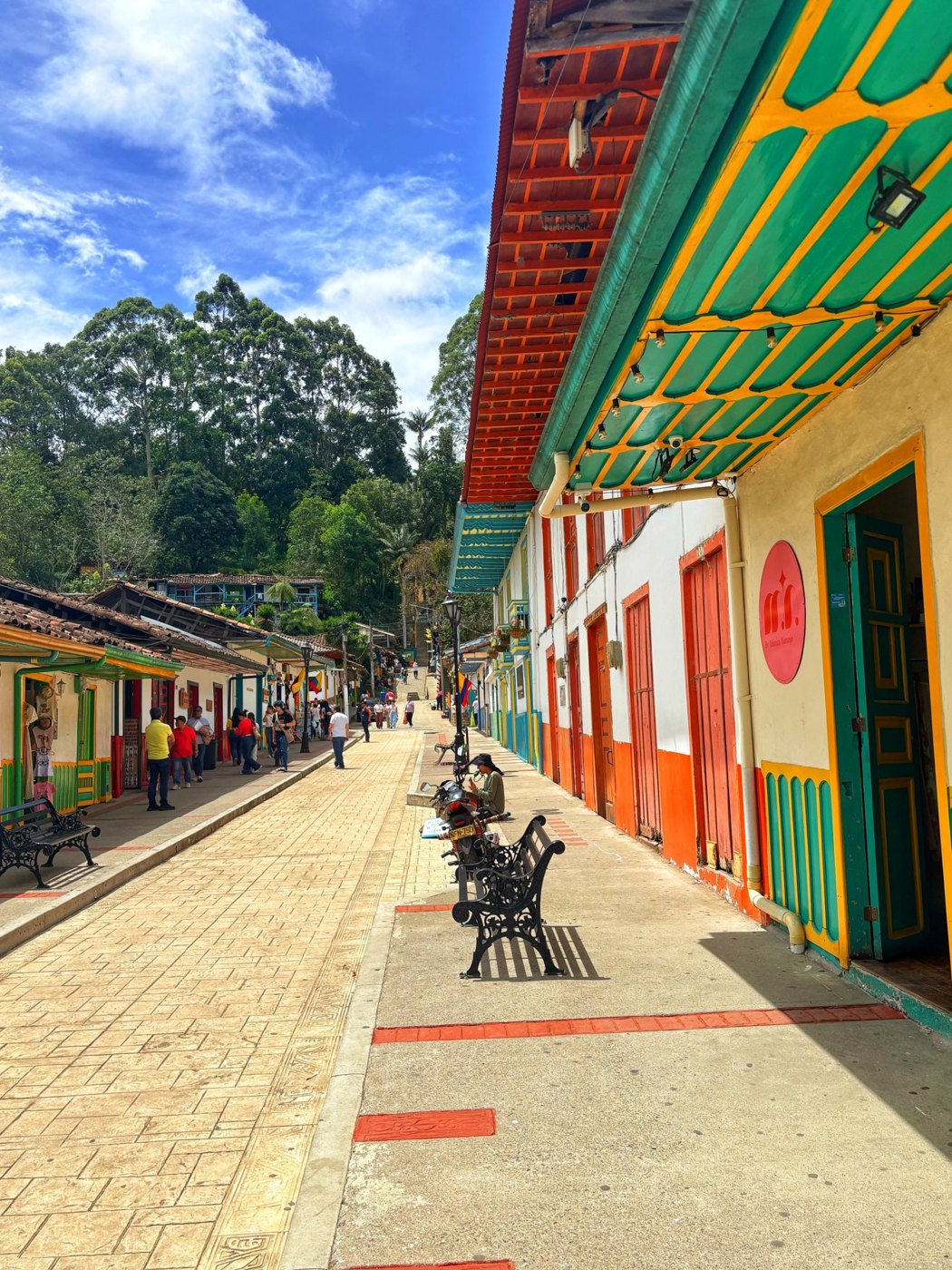 A street in a Colombian town with brightly painted façades, balconies and doors