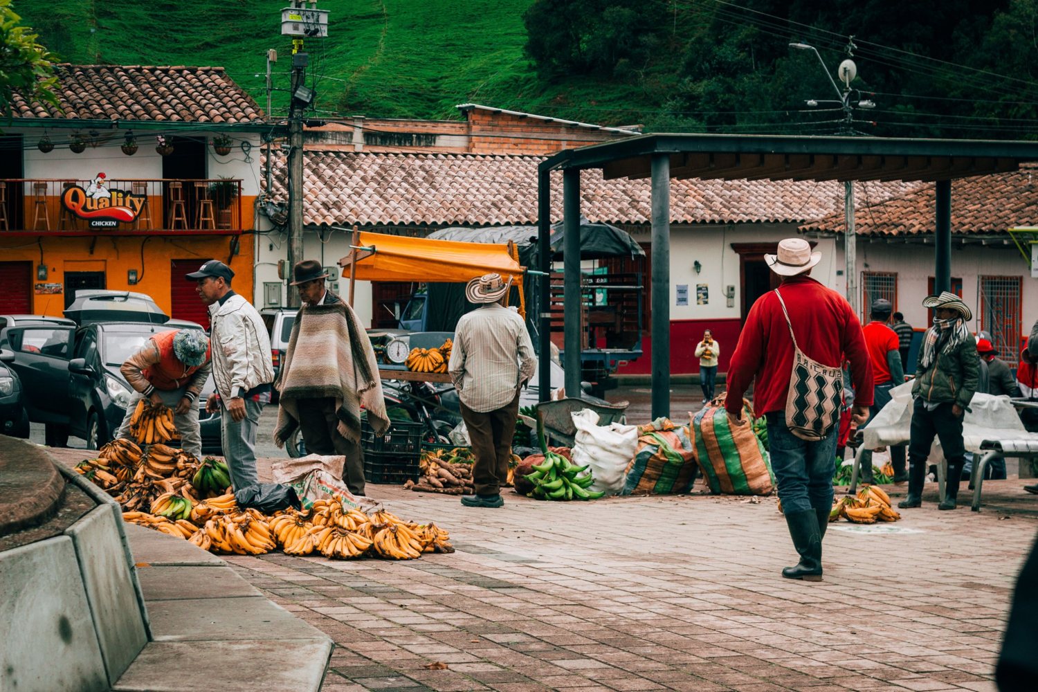 Farmers in hats and ruanas sell bunches of plantains in a town square